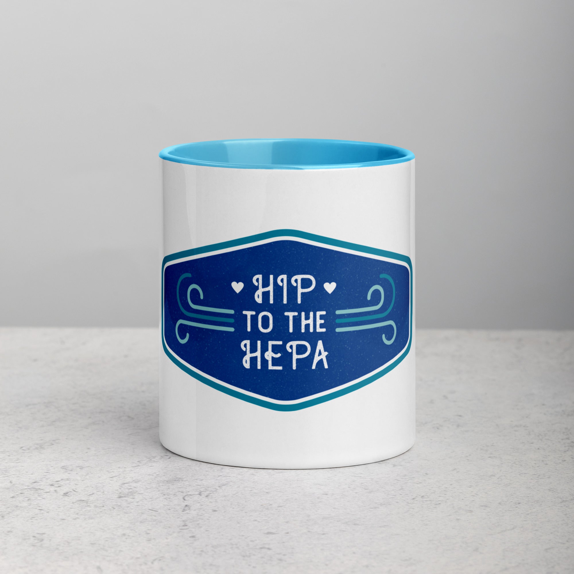 front facing white mug with blue interior and handle. Mug has blue logo image with text 'hip to the hepa'